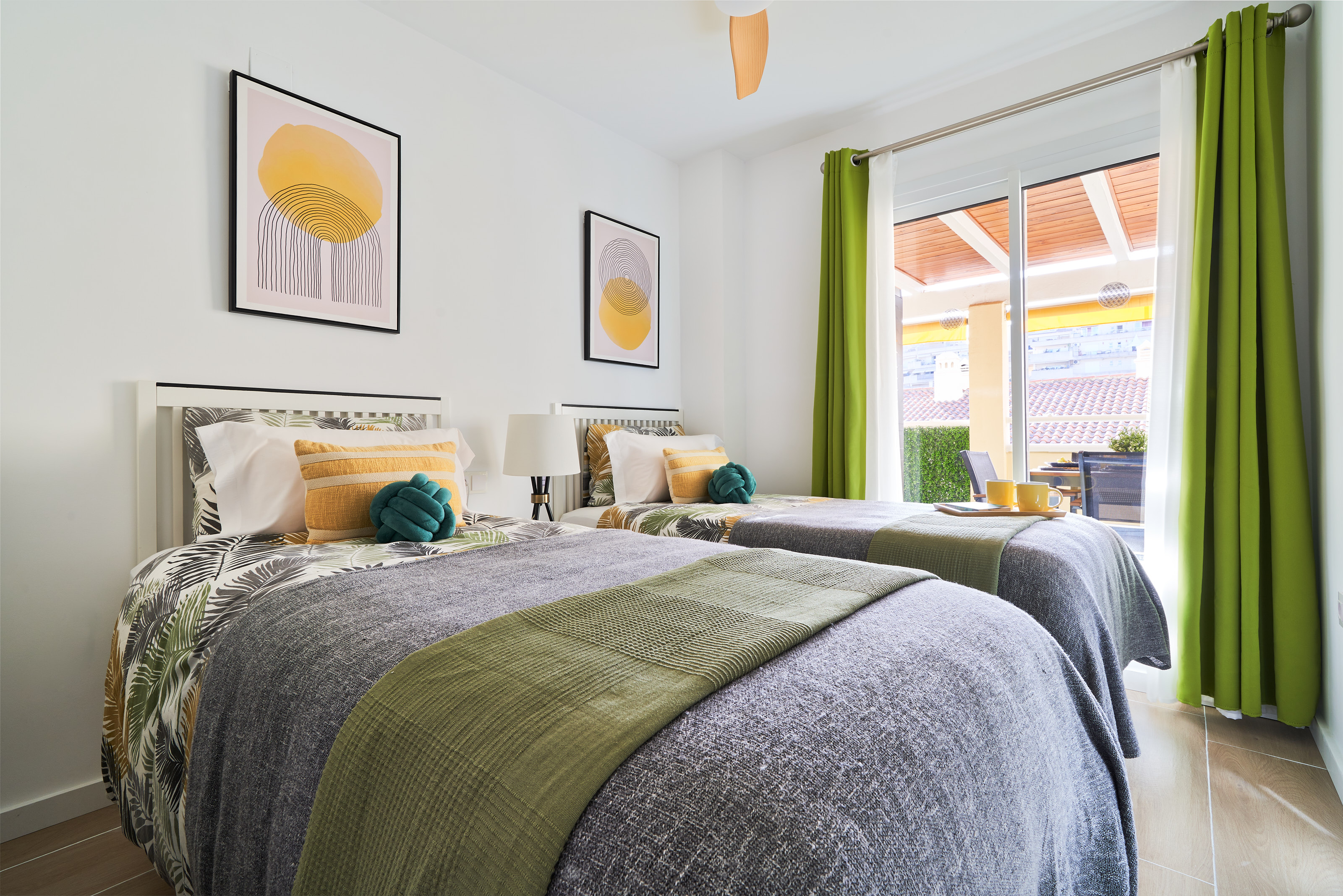 Bright and calming twin bedroom with tropical tones, soft linens, and direct access to the terrace — perfect for relaxed mornings and restful nights.