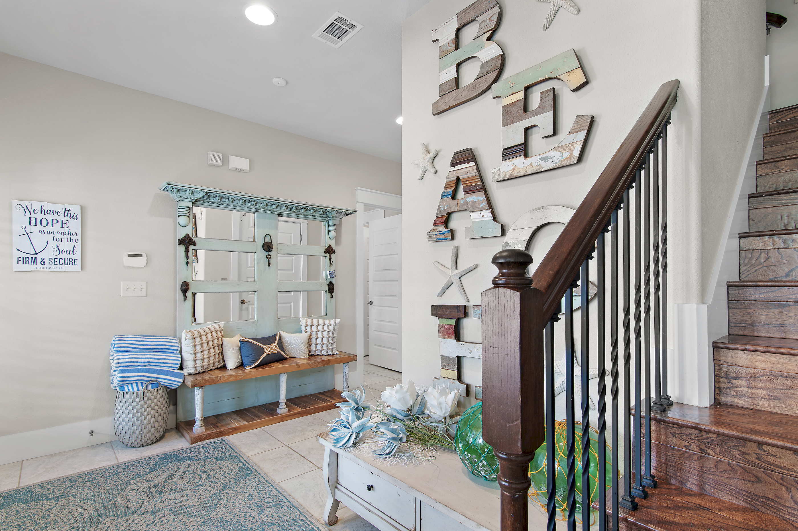 Bright coastal entryway with charming beach inspired décor, a welcoming bench, and beautiful details throughout.