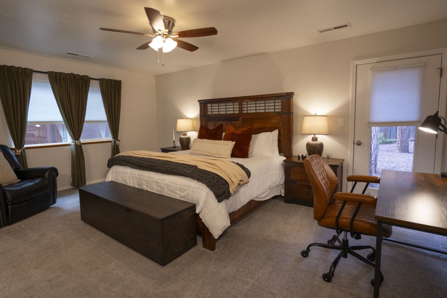 Spacious primary bedroom with a large king bed, work desk, closet storage, and comfortable seating.