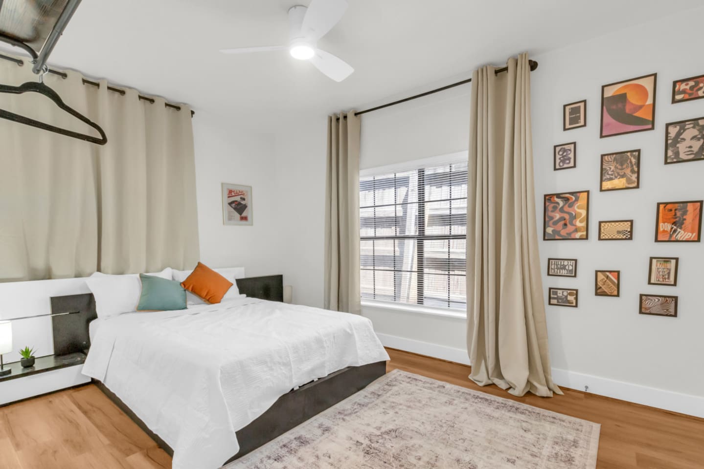 bedroom with queen bed, exposed closet with hangers, room darkening shades, and modern decor.