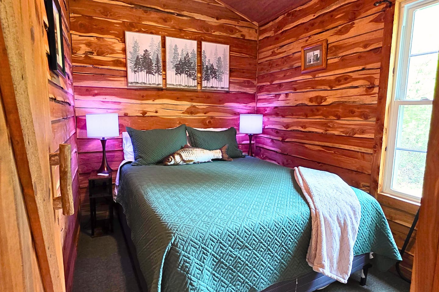 Drift off to sleep in the peaceful cabin bedroom, complete with cozy lighting, ceiling fan, rustic charm, and nature views right outside your window. 