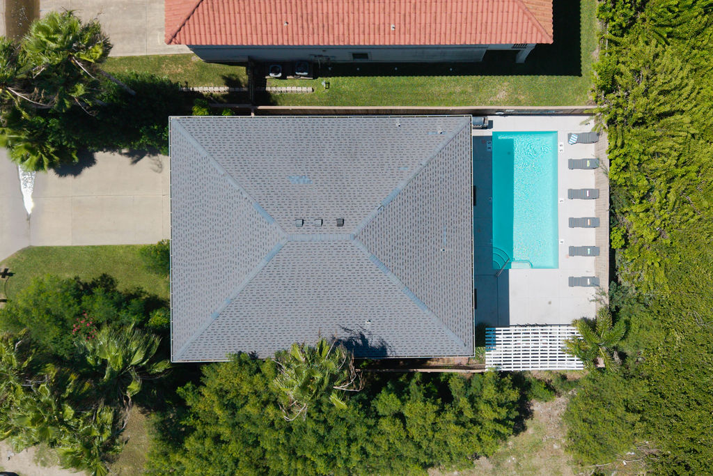 An aerial view of your private paradise! Take in the full beauty of the property — a stunning home surrounded by lush greenery, a sparkling pool, and inviting outdoor spaces made for unforgettable getaways.