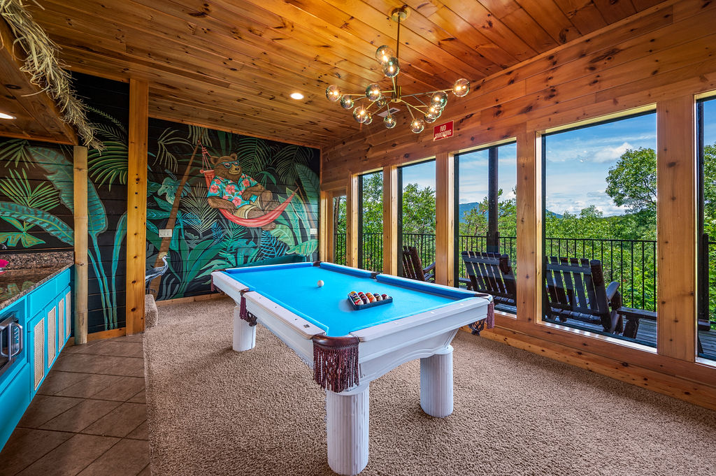 Game room with large windows offering a scenic mountain views and access to a balcony with rocking chairs
