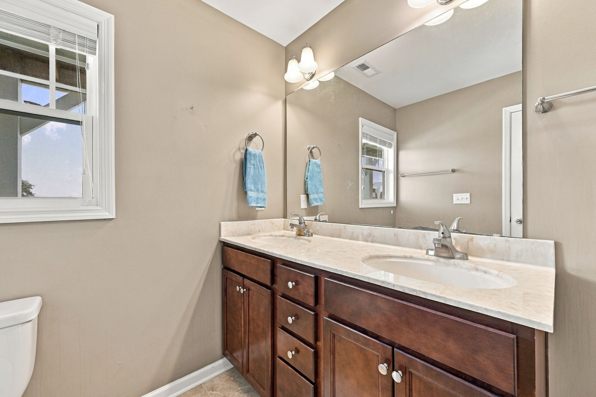 Getting ready is a breeze with dual sinks, ample vanity storage, and bright overhead lighting