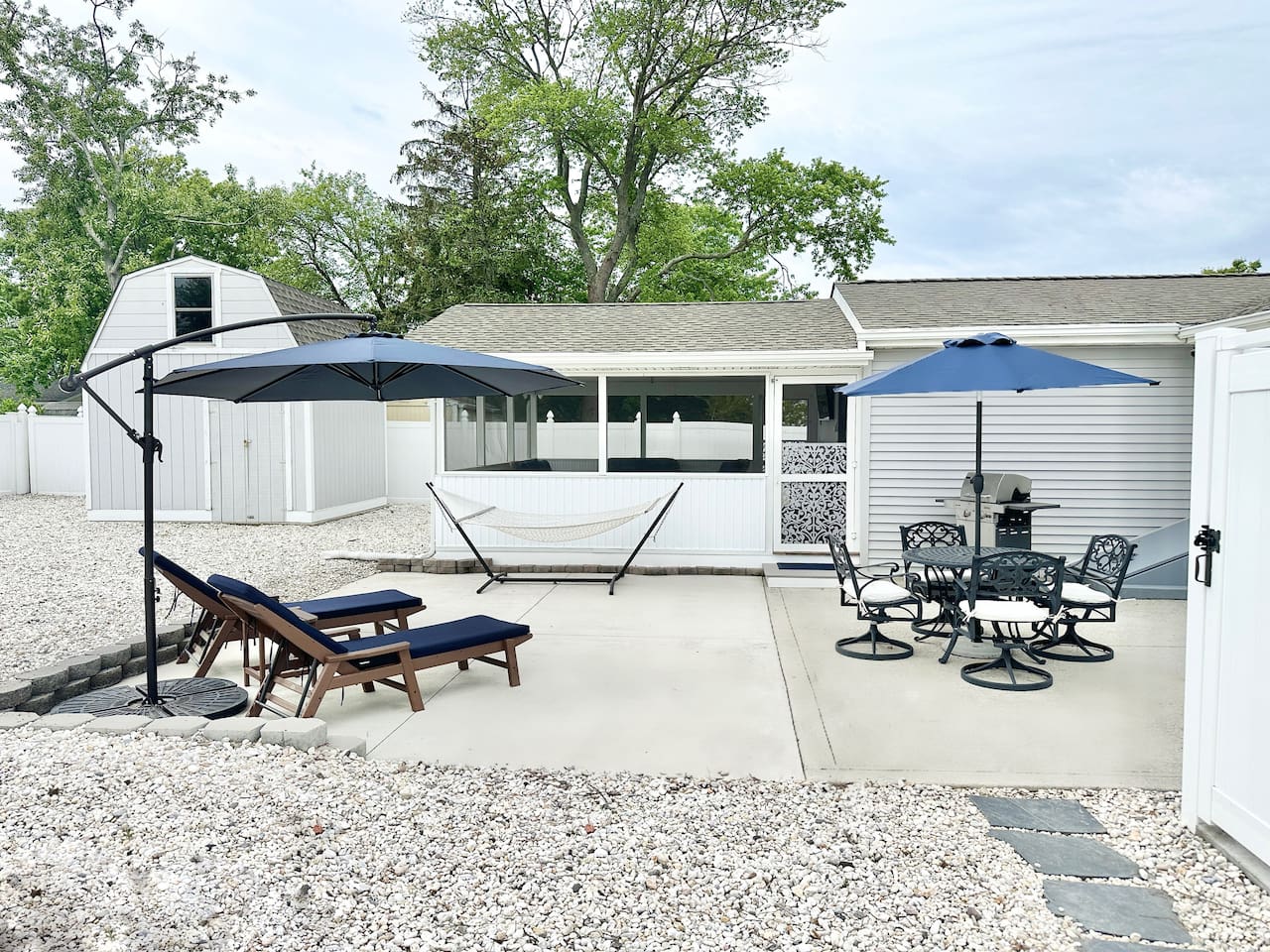 Maximize your vacation in our fully equipped backyard. Features include a gas grill, patio dining for four under a blue umbrella, lounge chairs for sunbathing, and a relaxing hammock. The perfect setup for a summer afternoon BBQ!
