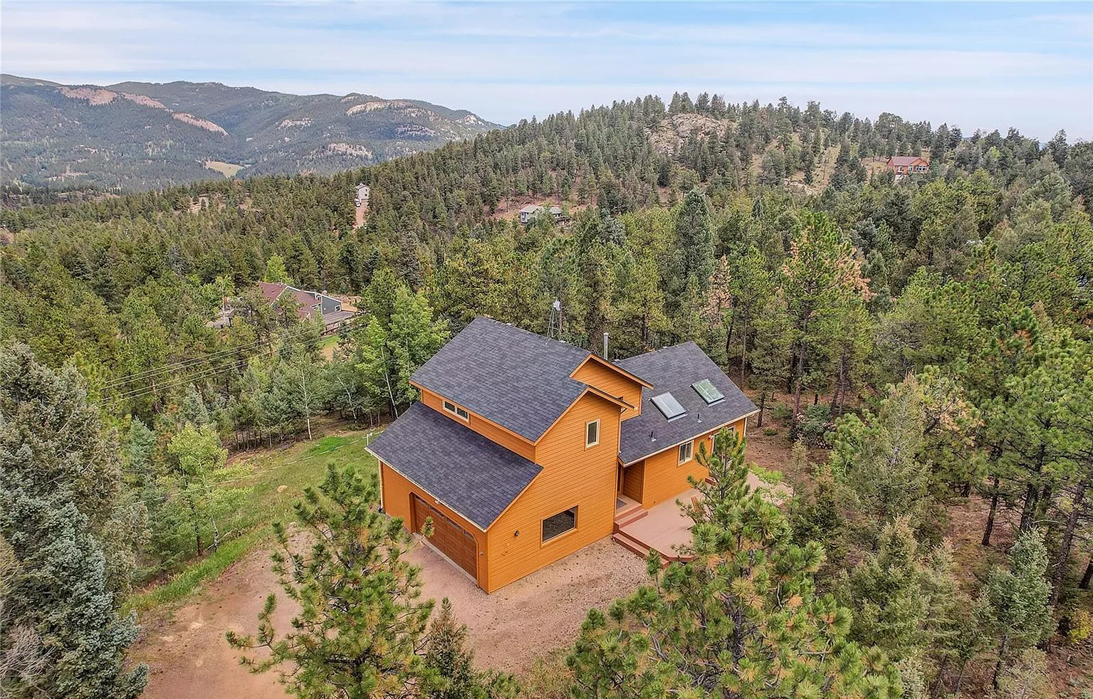 Aerial view showcasing the roofline, exterior siding, and surrounding trees.