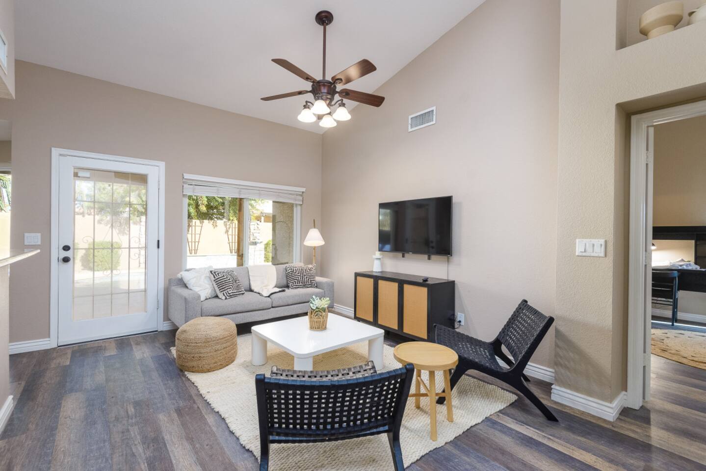 Sitting area with wall-mounted TV, comfortable seating, ceiling fan, and patio door access for relaxed downtime.