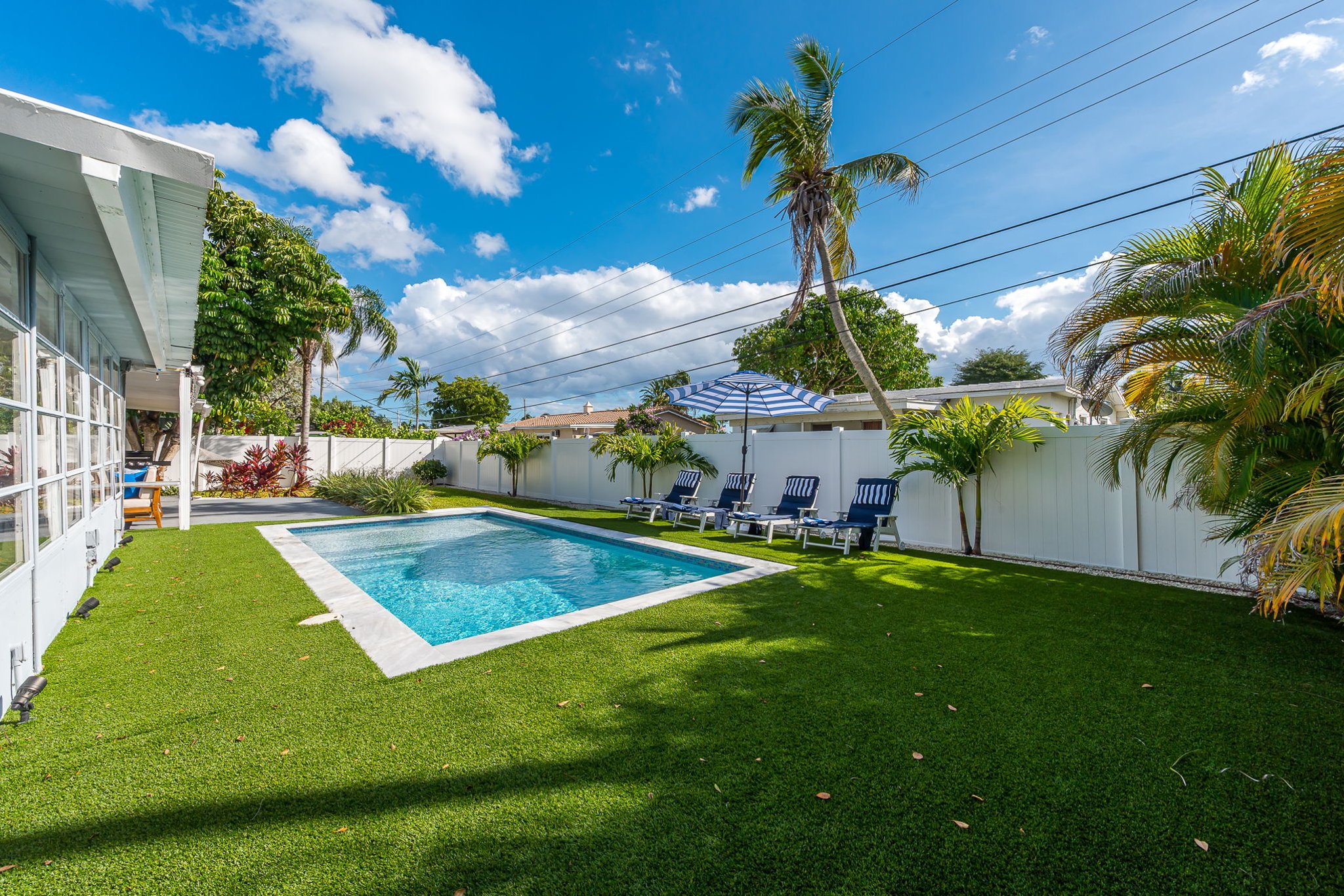 Dive into luxury with a sparkling heated saltwater pool, surrounded by lush palms, chic loungers, and modern turf for the perfect resort-style backyard escape.