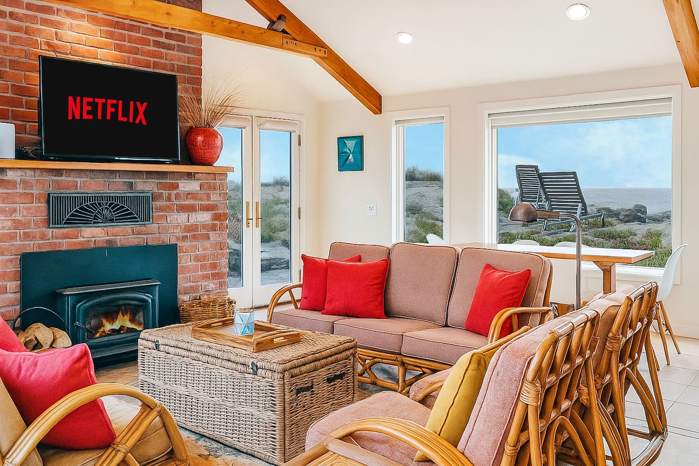 - Cozy living room with rattan seating, vibrant cushions, and brick fireplace  
- Large windows frame beautiful ocean views for a relaxing seaside vibe  
- Wall mounted TV with streaming options ensures entertainment for all guests  