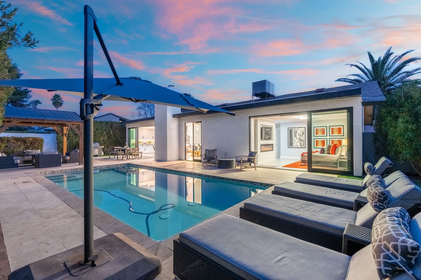 Capture the full essence of this entertainer’s dream—sunbeds, open indoor areas, pergola, and pool—glowing under the pastel dusk sky.