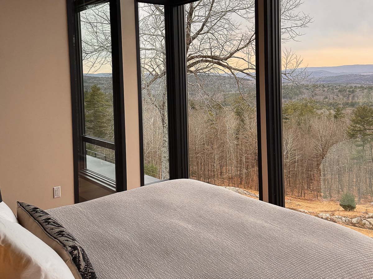 Primary Suite &mdash; west view from the bed, sunset across the valley, floor-to-ceiling glass on three sides