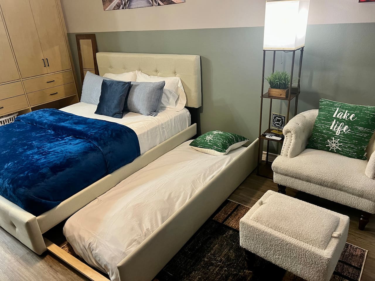 Queen bed with a twin pull-out underneath, plus a chair and ottoman for relaxing.
