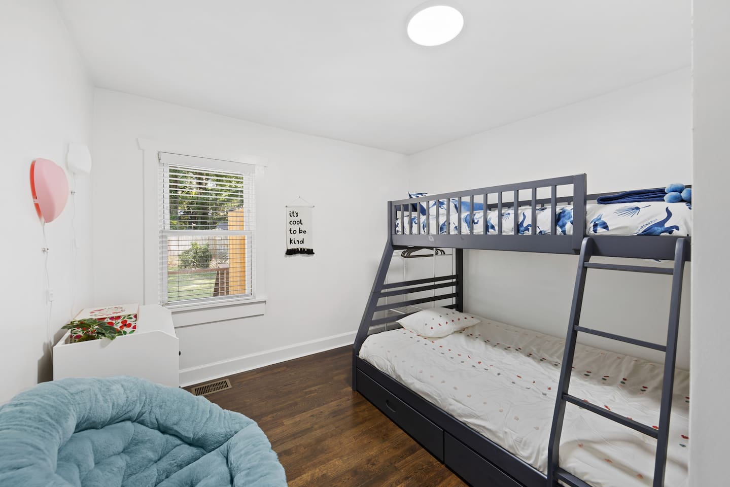 Kids bedroom features bunkbed with full size bed on the bottom and twin size upper bunk.  Papasan chair for reading.  Window looks out at backyard.