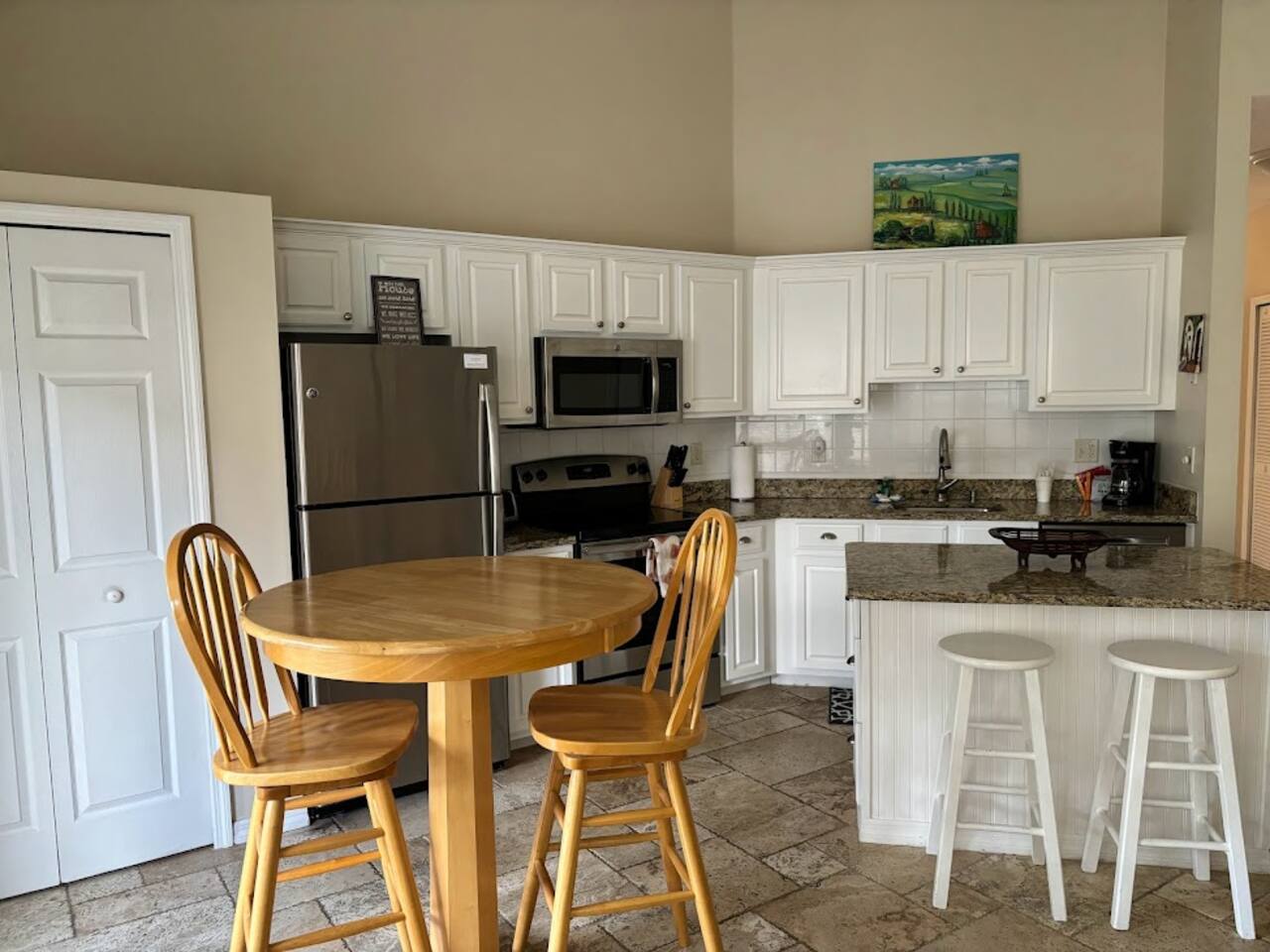 Open kitchen and dining area featuring white cabinetry, granite countertops, breakfast bar seating, and a round dining table.