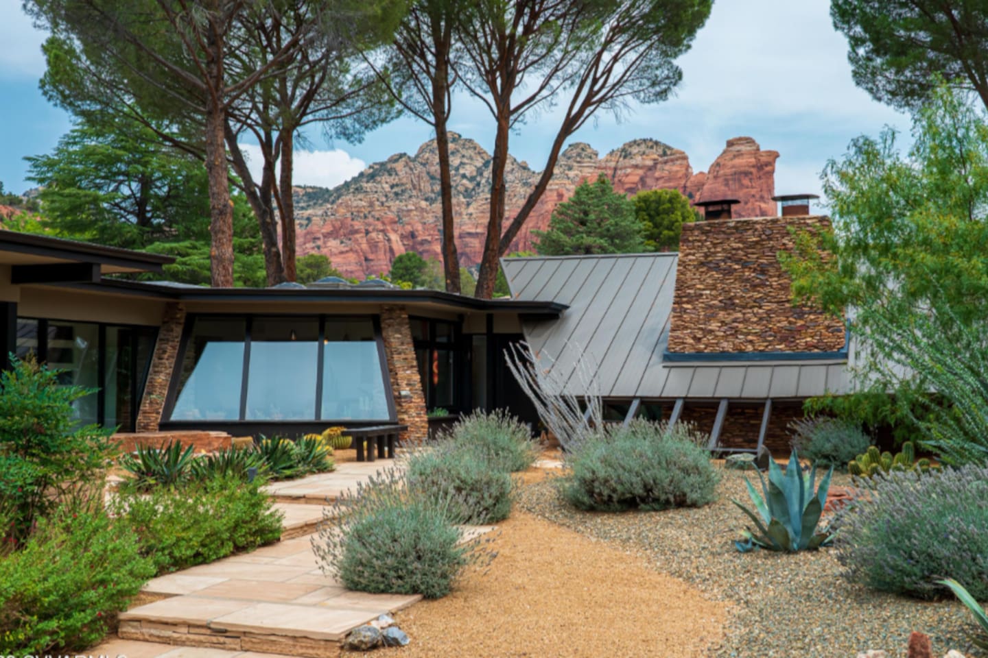 Beautifully landscaped courtyard with native desert plants and striking red rock views surrounding the modern architecture.