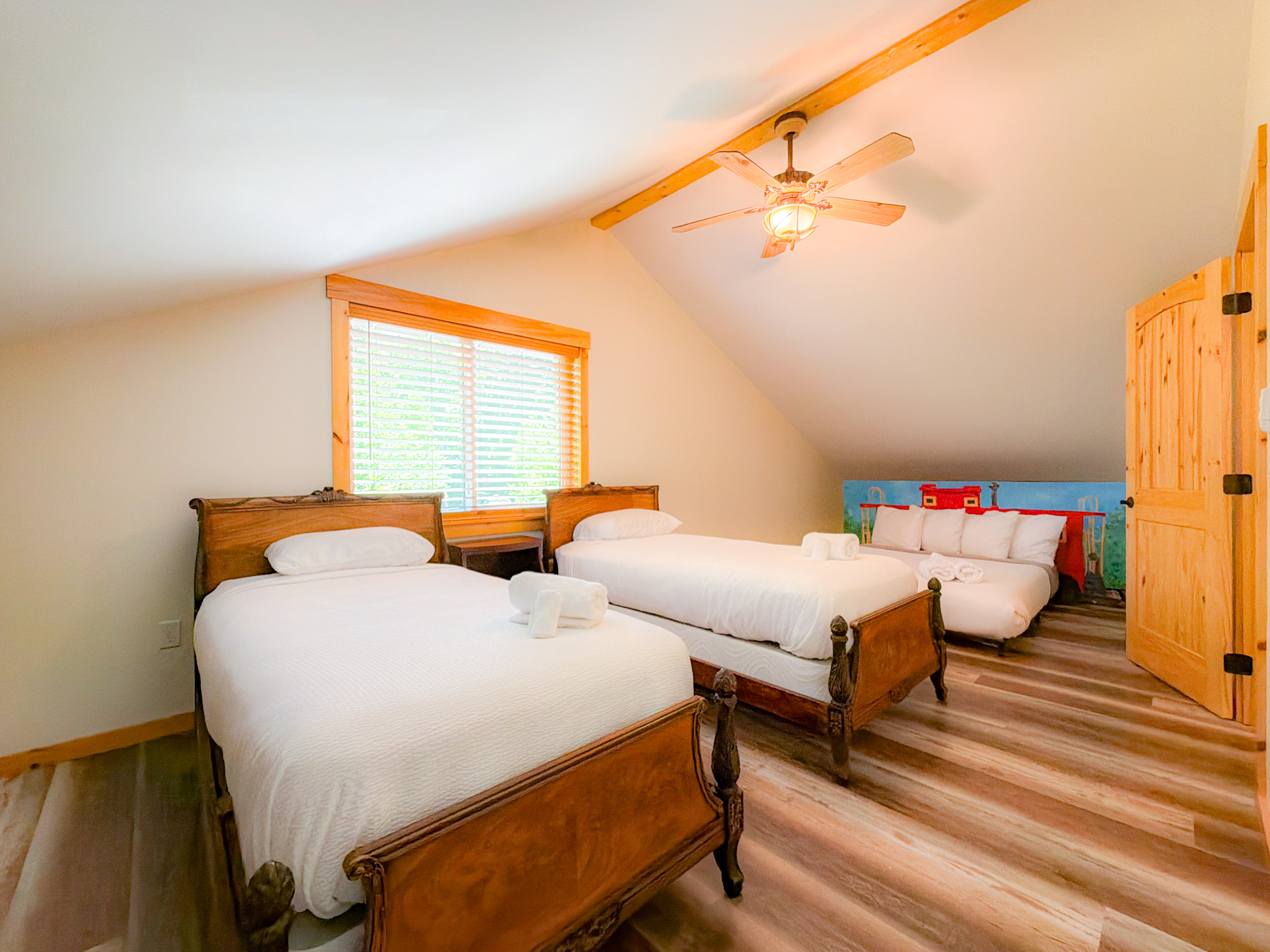 The Caboose themed room is setup for the kiddos who two twin beds na da low profile Queen Bed with a handprinted train backdrop.
