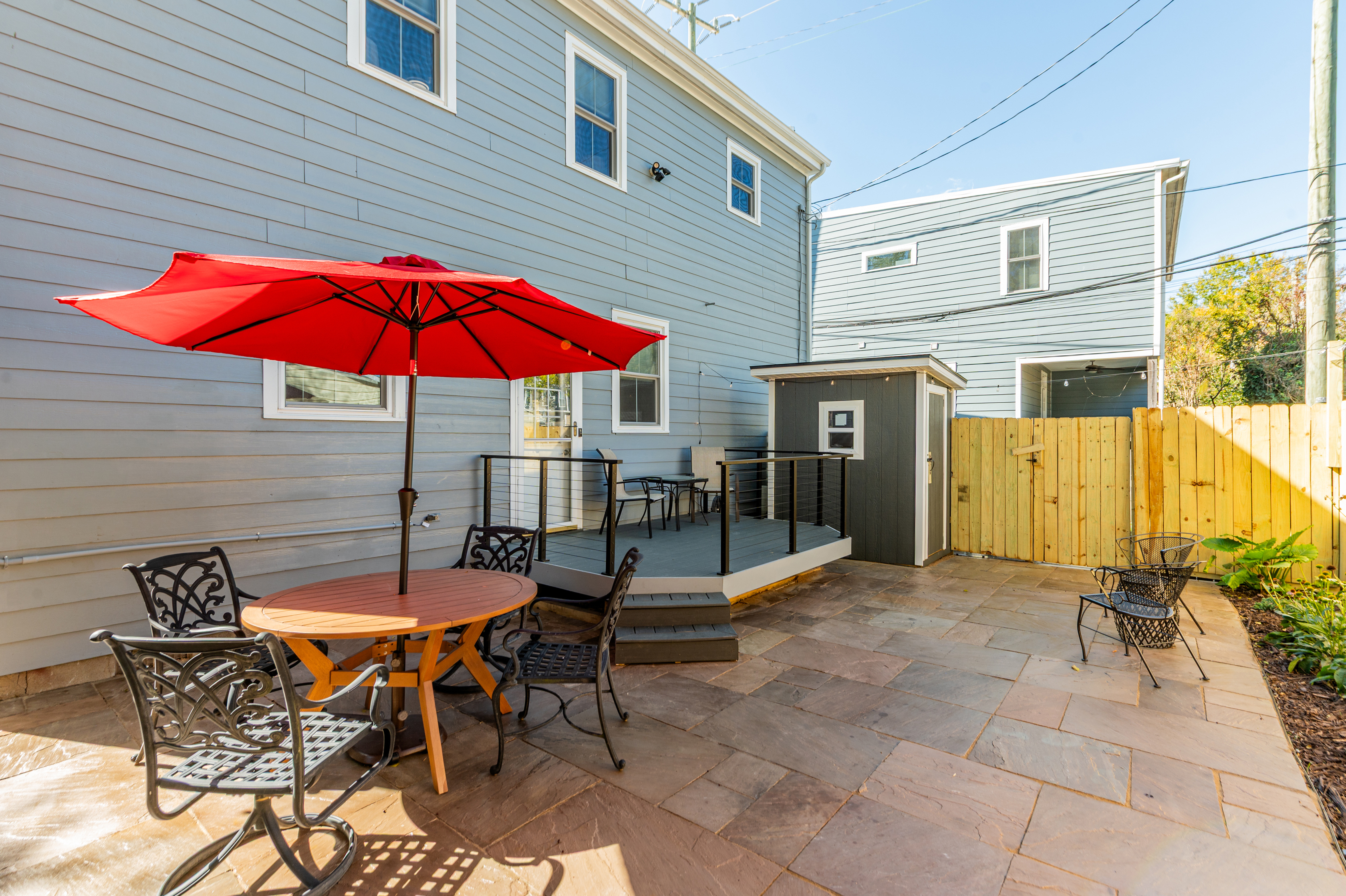 Outdoor Oasis: Relax under the vibrant red umbrella on your private patio, perfect for gatherings!