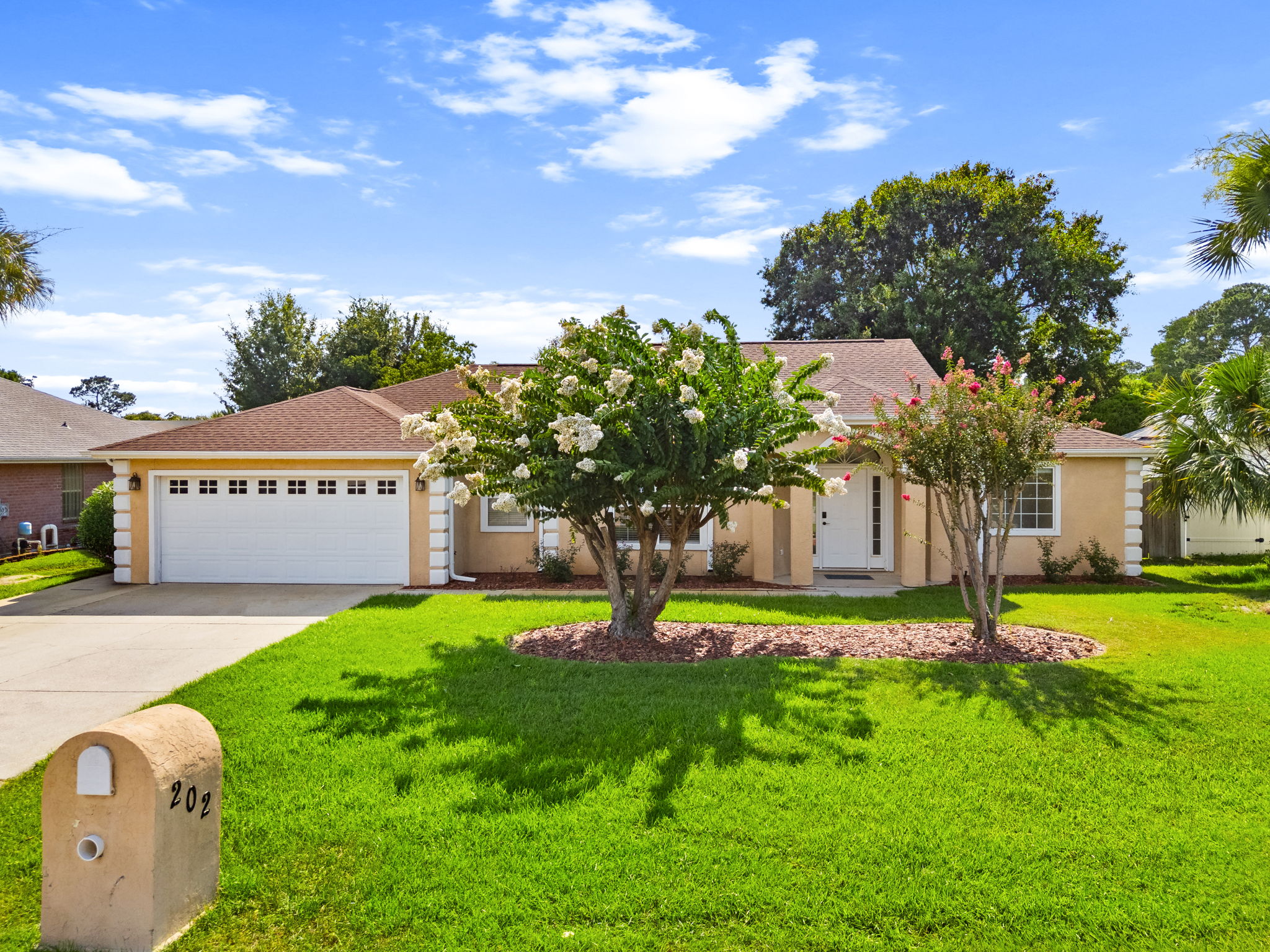 Welcome to Treasure Palms Villa! Our well-maintained single-story vacation home with a manicured green lawn, two blooming pink and white crepe myrtle trees in the front yard, a concrete driveway leading to your private entry. 
