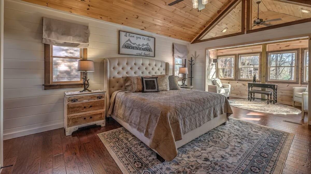 Primary bedroom retreat with vaulted wood ceilings, plush bedding, and peaceful forest views.
