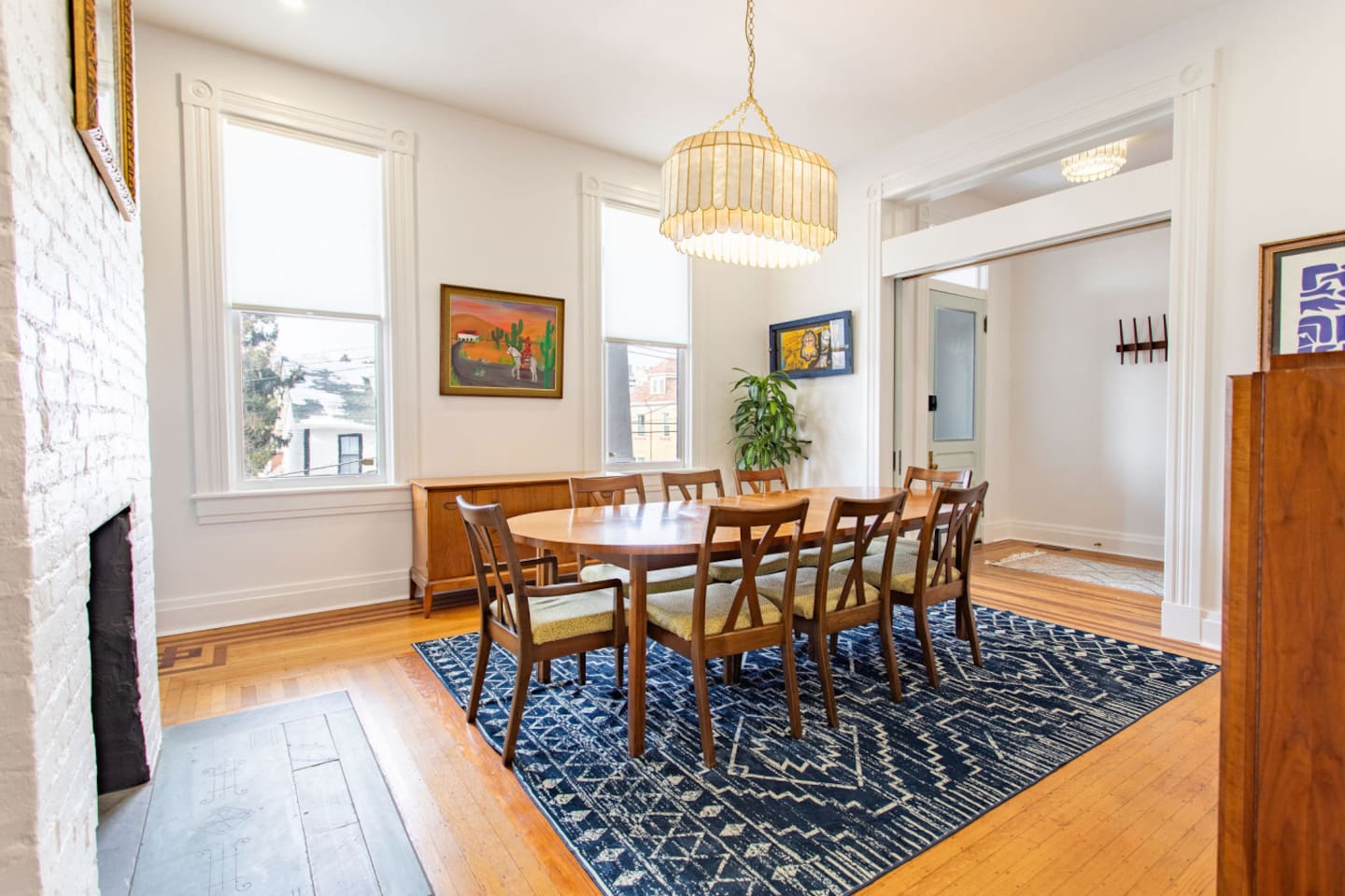 An elegant 8-seater dining table positioned near large windows, allowing plenty of natural light to flood the space, perfect for both family gatherings and entertaining guests.