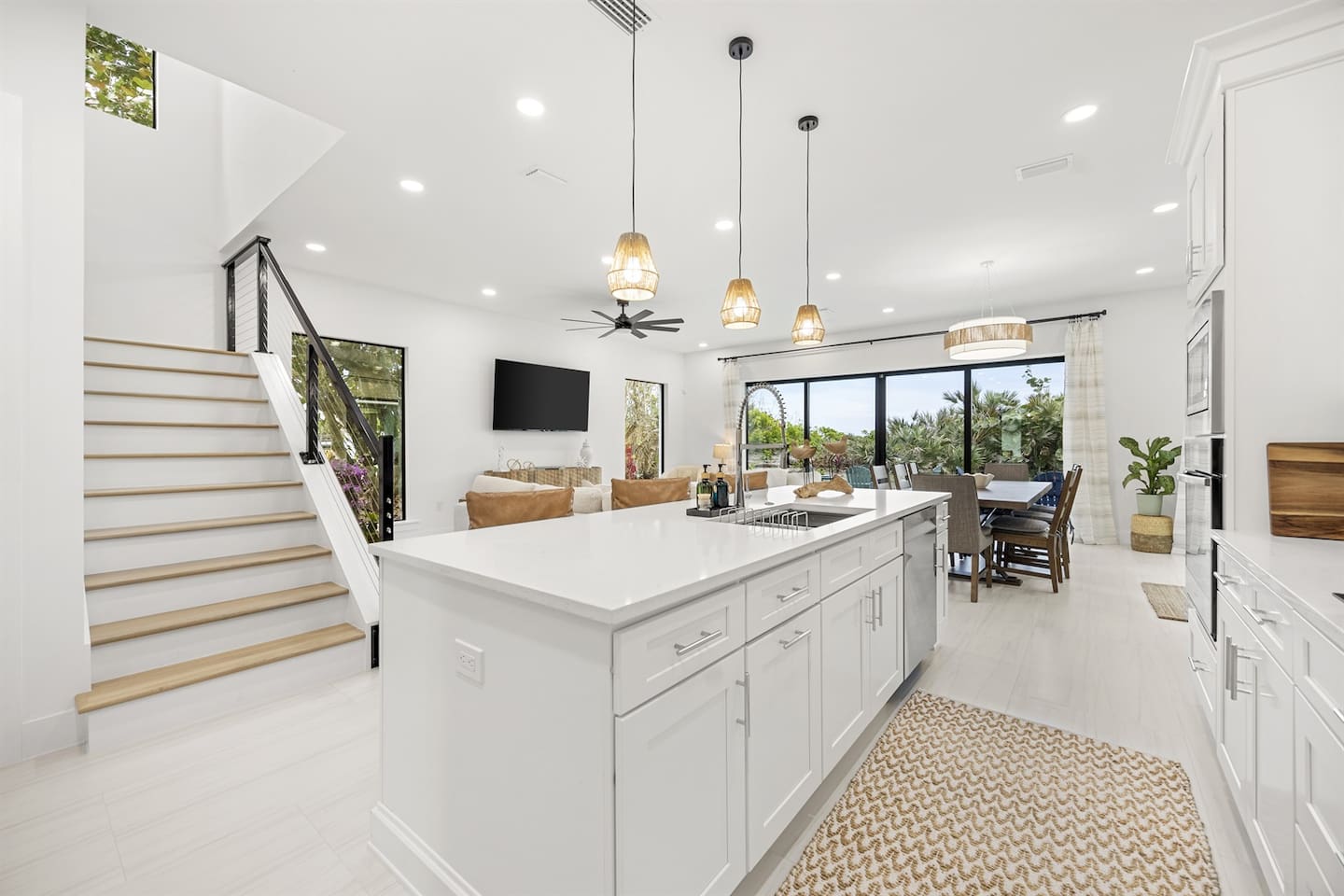 An overview of the kitchen island, looking out to the dining and living room, with a glimpse of the staircase leading upstairs, creating an open and inviting space.