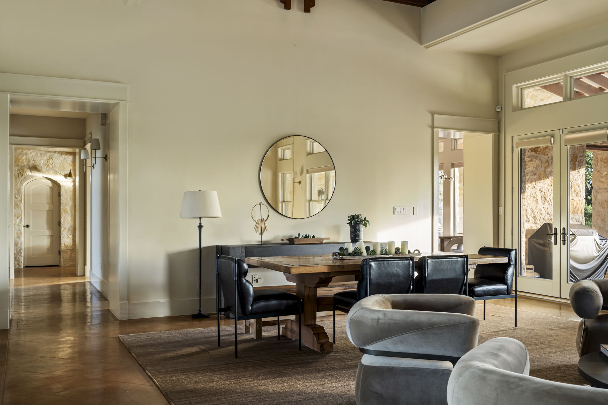 A stylish round mirror reflects the elegant dining area and spacious living room.