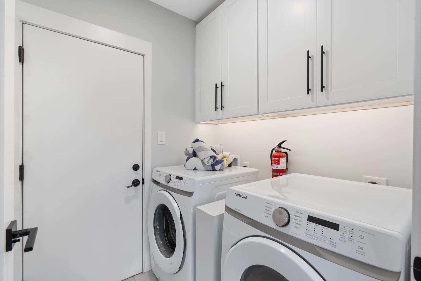 Fully equipped laundry room with washer, dryer, overhead storage, and thoughtful touches for a hassle-free stay