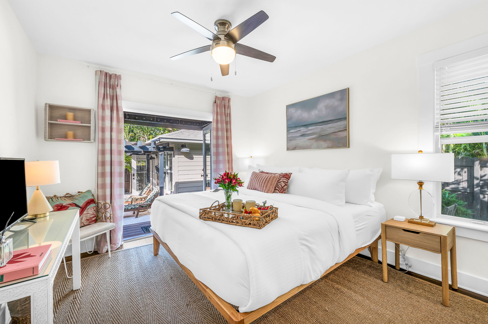 Serene king primary suite featuring a smart TV, private en-suite bathroom, and elegant French doors that open directly to the pool—perfect for seamless indoor-outdoor living and relaxing mornings or evenings.
