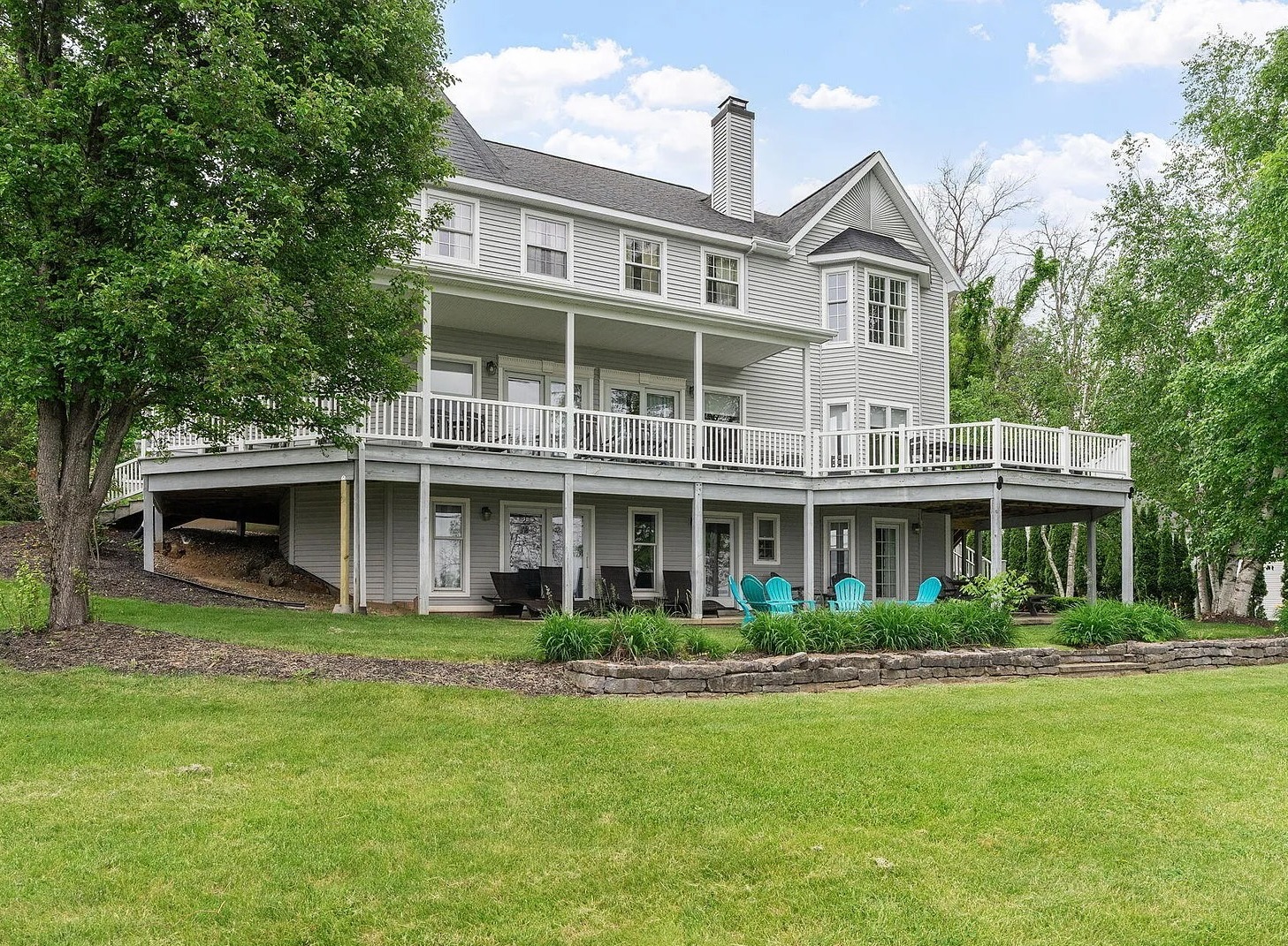 A striking lakefront home featuring multiple levels of outdoor living, distinctive architectural details, and stunning views of Saratoga Lake.