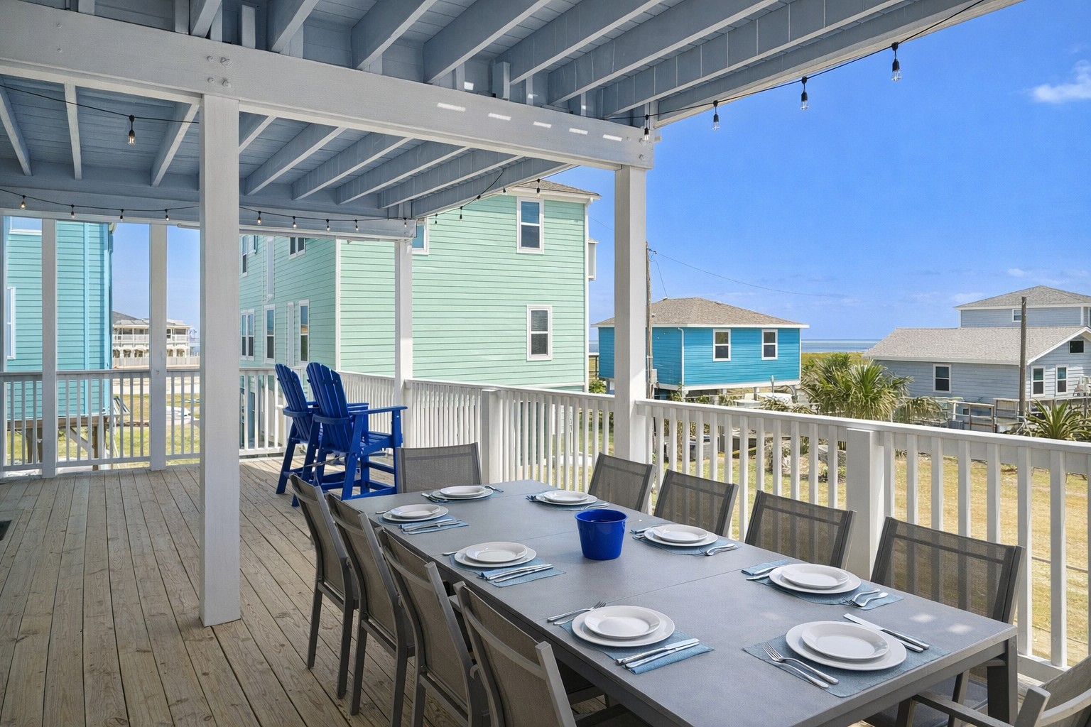 Covered Outdoor Dining (Main Level Deck): Large table seating for group meals with coastal views.