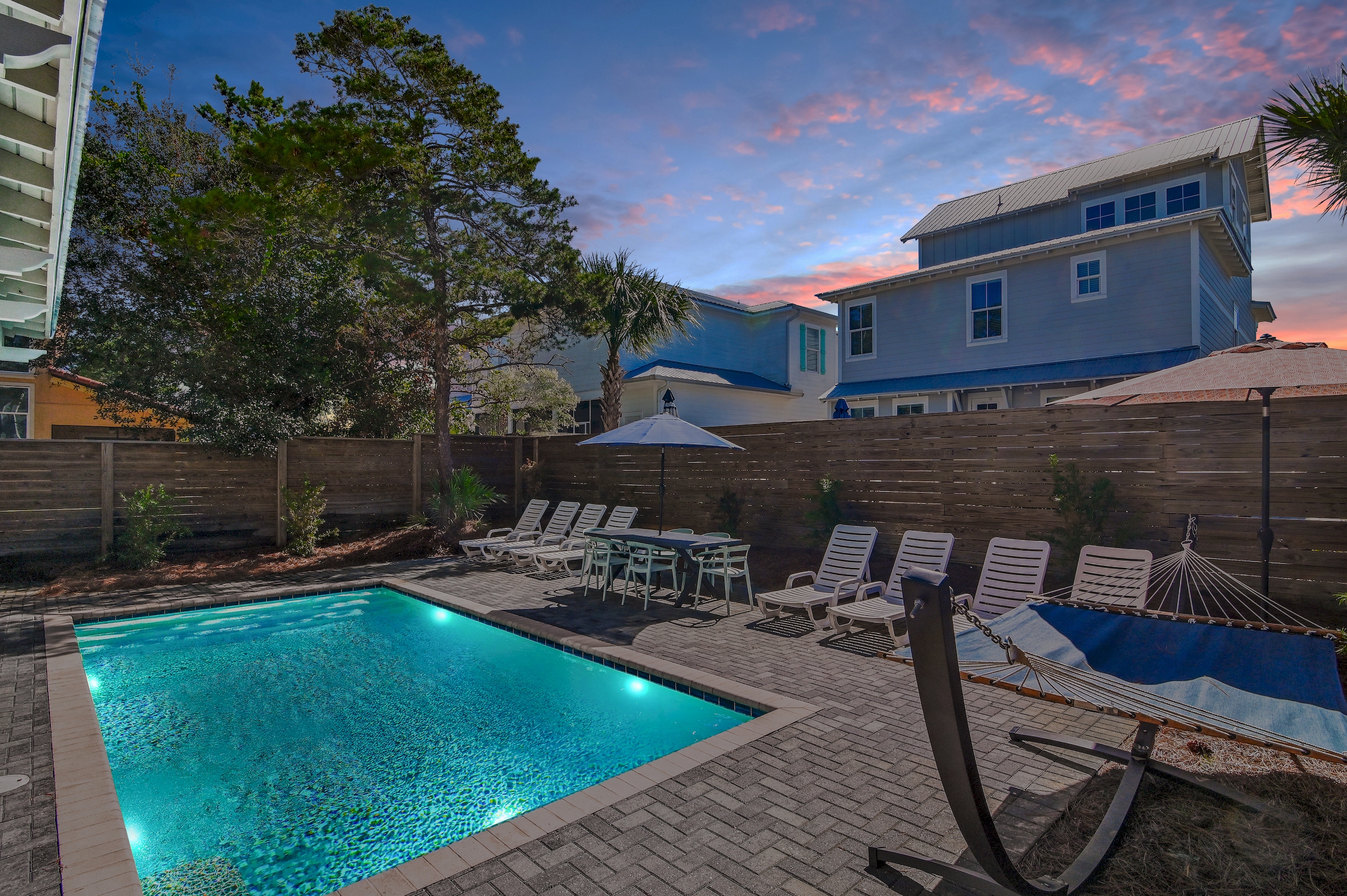 Beautiful backyard with pool, hammocks, loungers, umbrellas, and outdoor grill.
