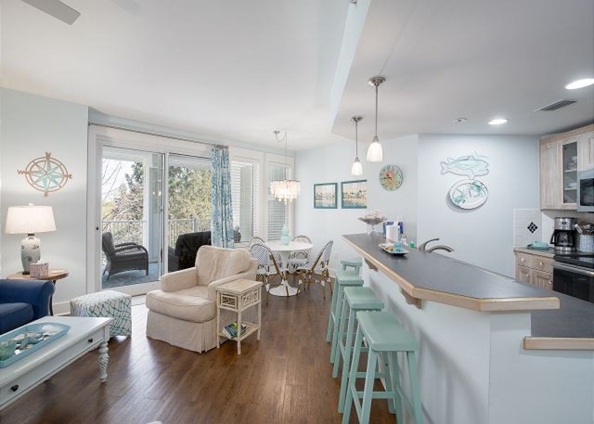 Open living area with breakfast bar seating, dining nook and sliding doors to the balcony
