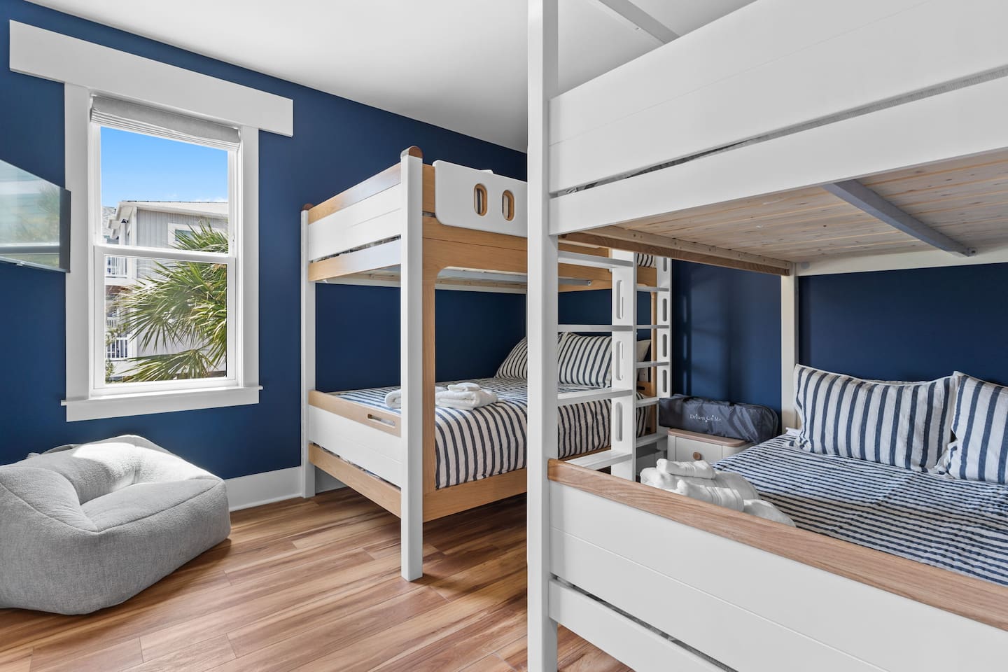 The downstairs bunk room includes a Queen-Over-Queen bunk bed + a Full-Over-Full bunk bed with private en-suite bathroom (tub/shower) & 32” smart TV. Child-sized seating adds to the charm.