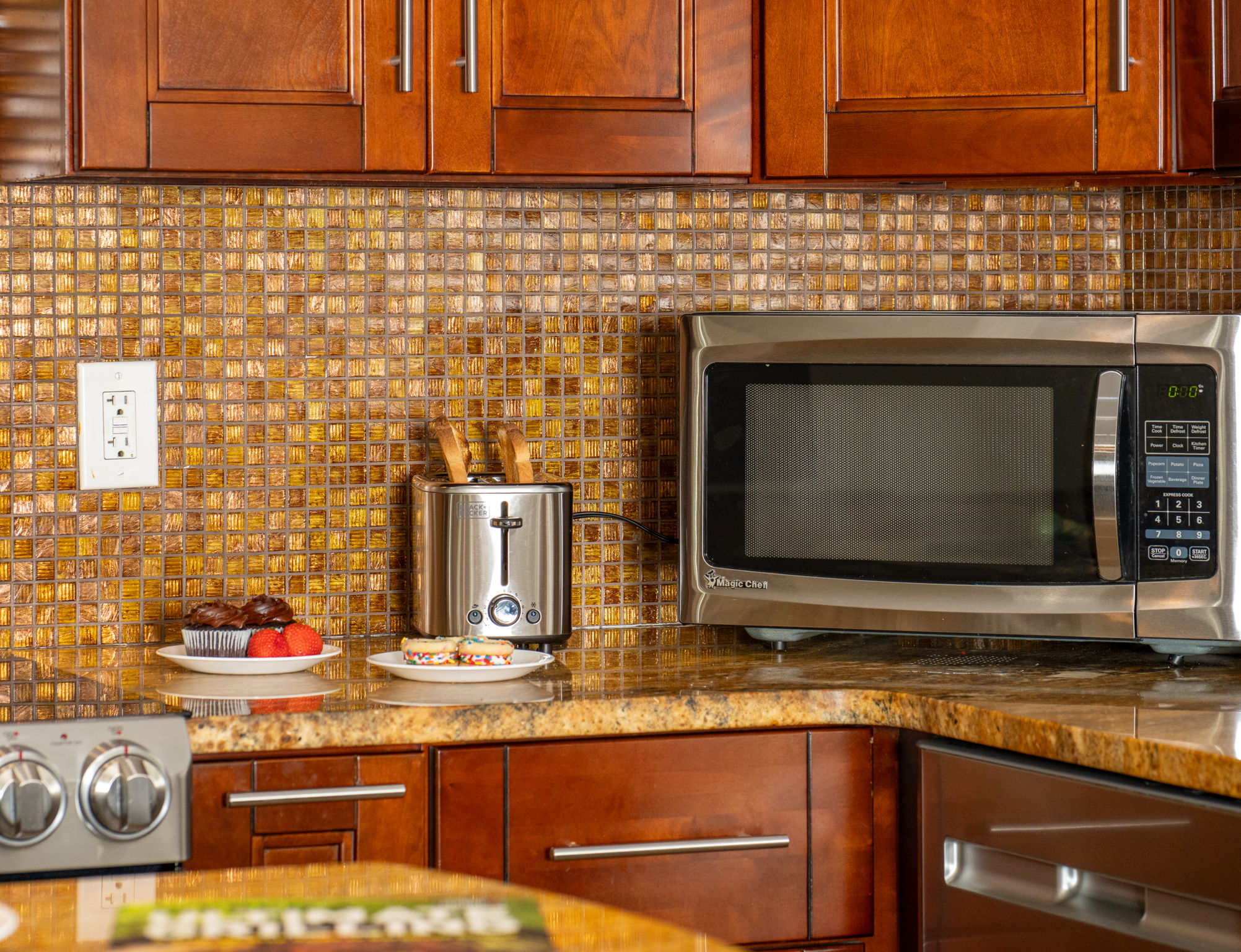 A golden mosaic backsplash brings texture and sparkle to the space, tying together the cabinetry and granite countertops.