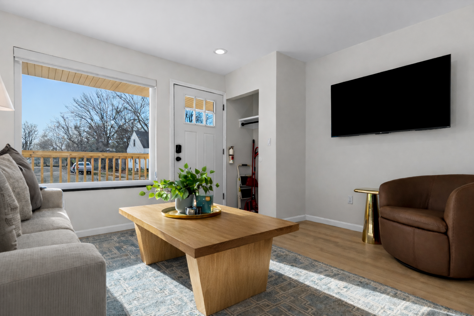 Bright, stylish living room with smart TV, cozy seating, and large windows that fill the space with natural light and fresh neighborhood views.