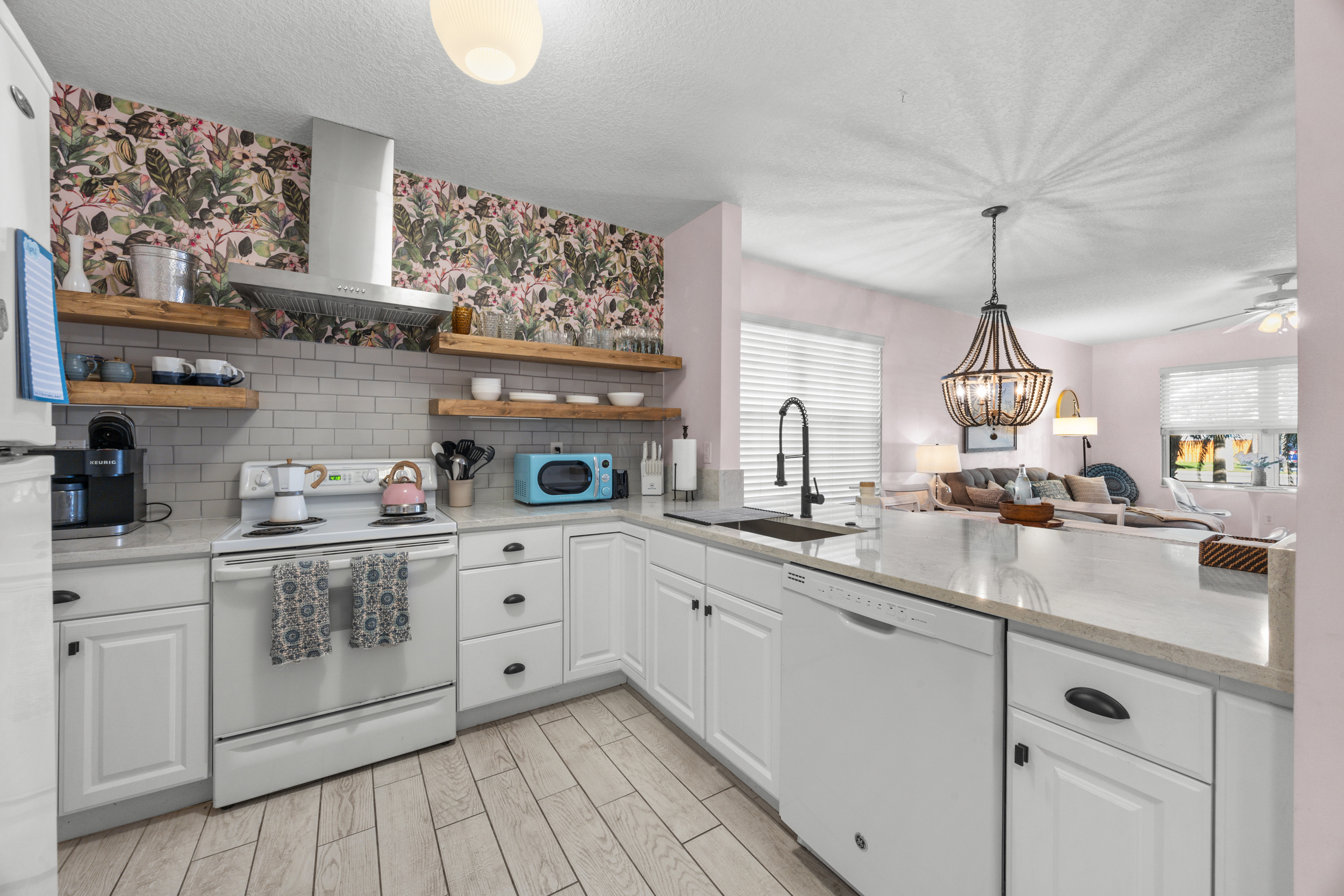 Open‑concept updated kitchen and living space with floating shelves and a bright coastal vibe.

