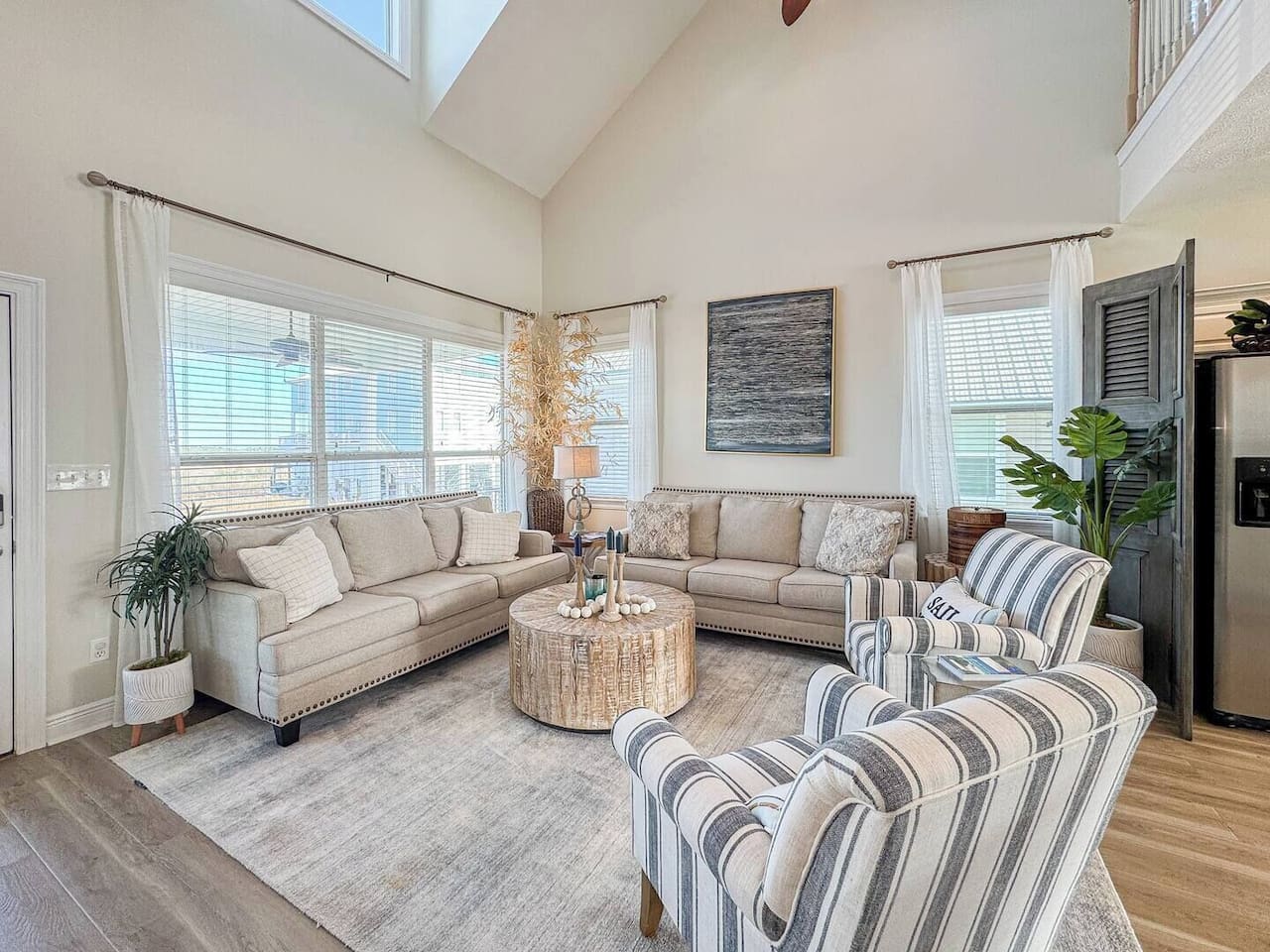 Light-filled living area with comfortable seating, coastal accents, and an open layout that flows into the kitchen—perfect for relaxing together.