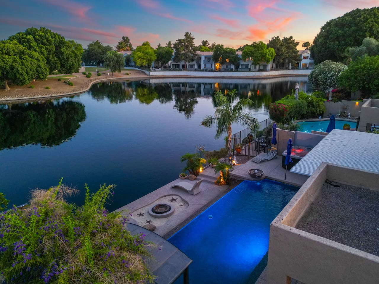 The fire bowl flickers at the water's edge as the lake mirrors the sunset sky — settle into the lakeside patio and let the evening unfold at its own pace.