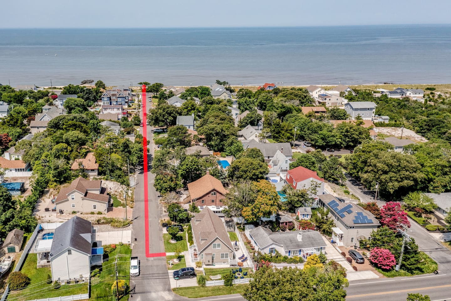 Check out this bird's-eye view of the neighborhood! The red line shows the easy, straight walk from the house down to the sandy shores of the bay. It’s just a quick stroll before you're standing right at the water's edge.