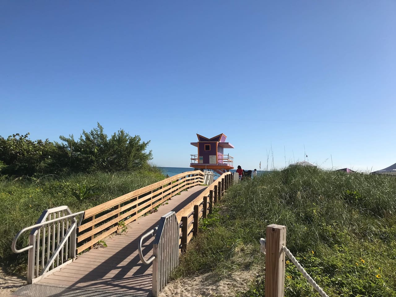 Wooden boardwalk through protected dunes to the beach, art deco lifeguard stand ahead