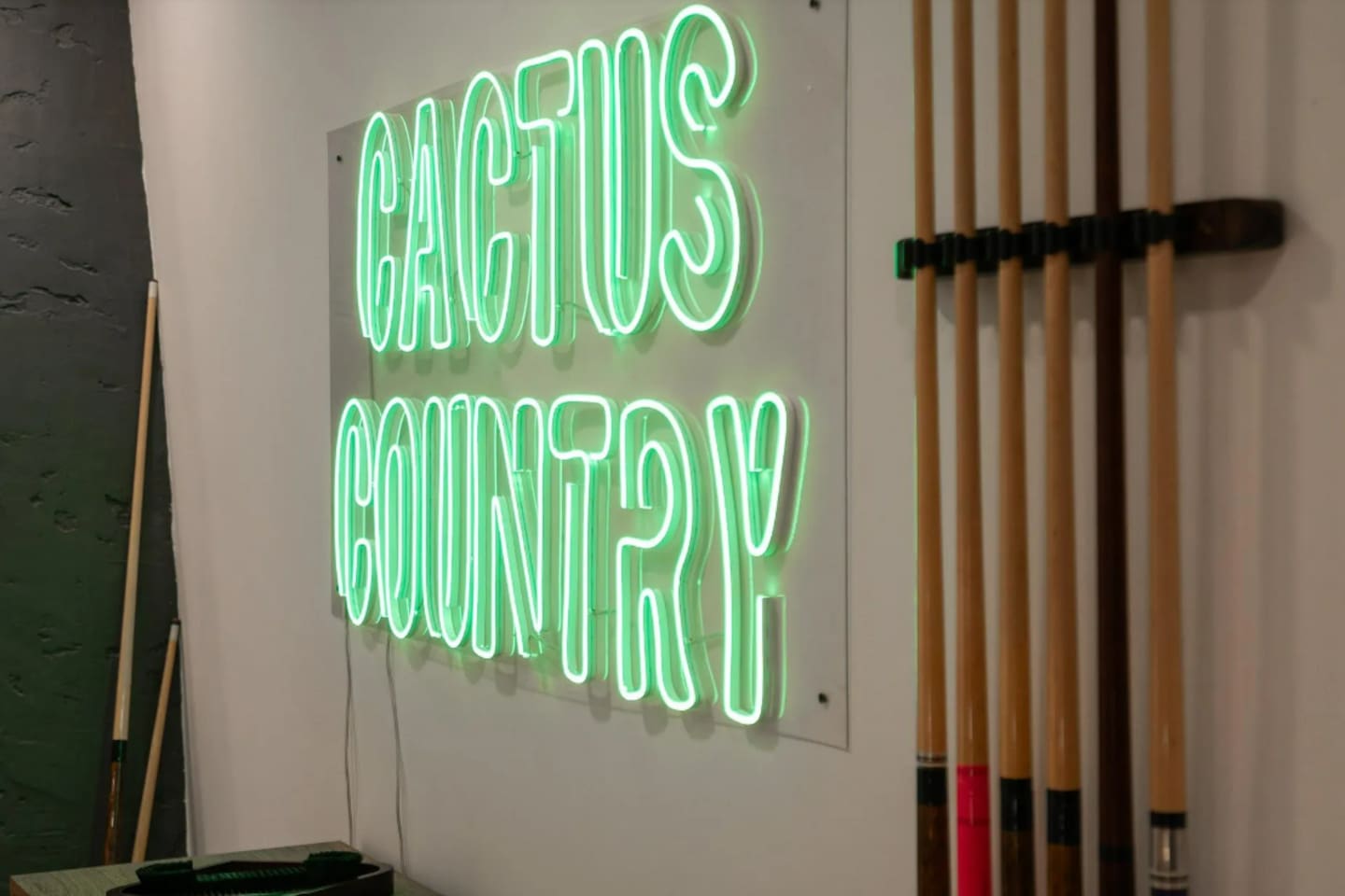 Custom neon signage and a full cue rack complete the game room's laid-back, playful vibe.