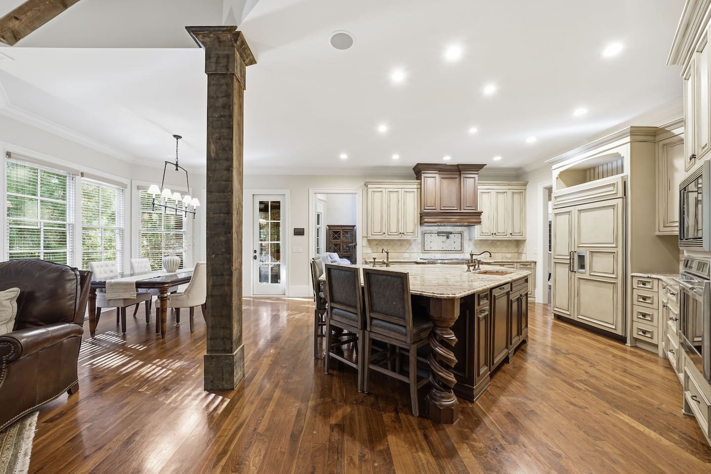 This open kitchen features beautiful cream wood cabinetry, sleek granite countertops, and an island that comfortably seats four. The bright, airy design makes it the perfect place to cook, gather, and share meals together.