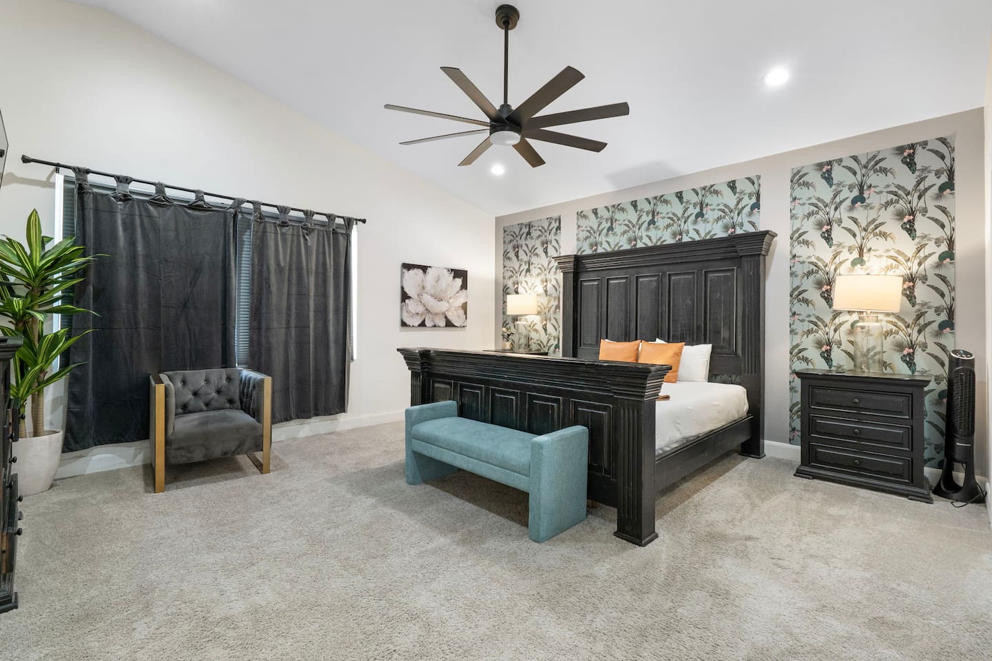 Luxe bedroom with statement black bed frame, botanical wallpaper, and spa-like seating area.