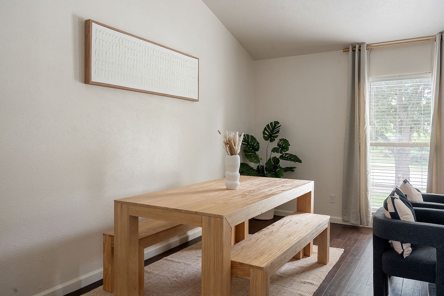 This inviting dining area features a sleek wooden table with matching benches, enhanced by natural light from the large window and tasteful decor.
