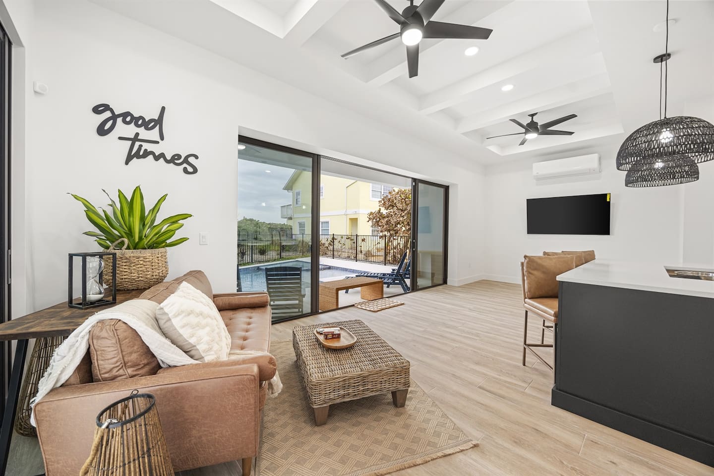The Cabana/event room features an elegant sofa and table with tasteful decorations, a glass sliding door showcasing a stunning outdoor view, and a stylish ambiance that invites you to relax and enjoy 'good times' in comfort