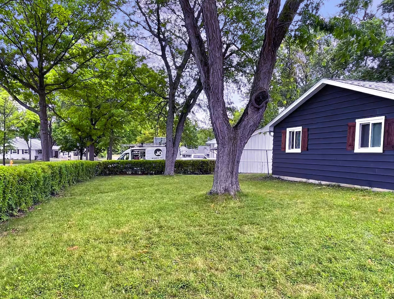 Mature shade trees and a tucked-away hedge line make this backyard feel like your own quiet retreat.