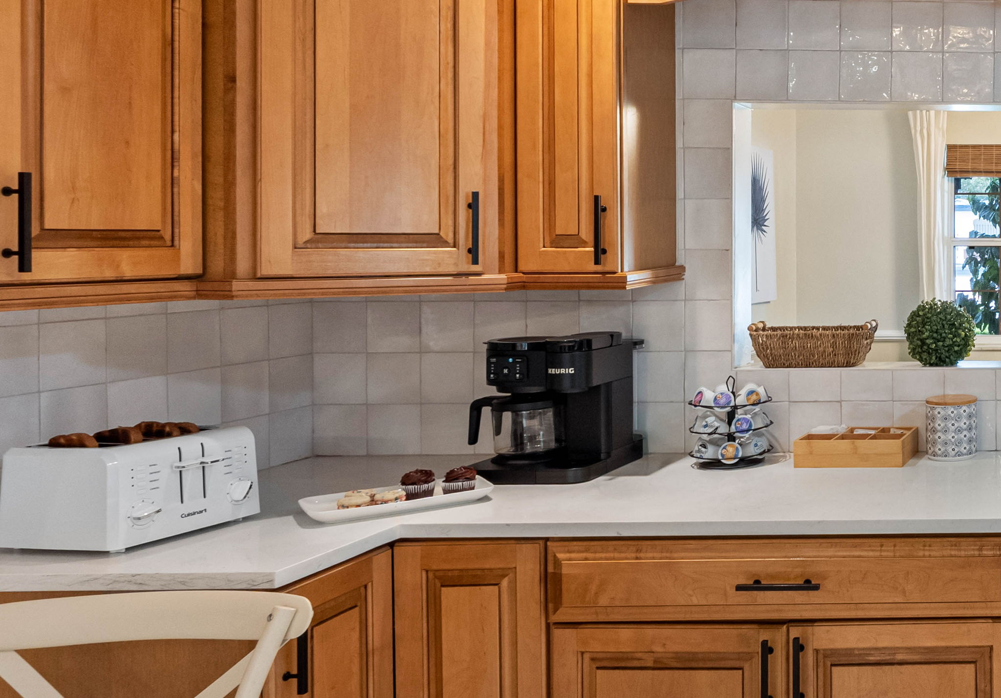 Natural wood cabinets and white quartz countertops create a timeless and inviting kitchen design.