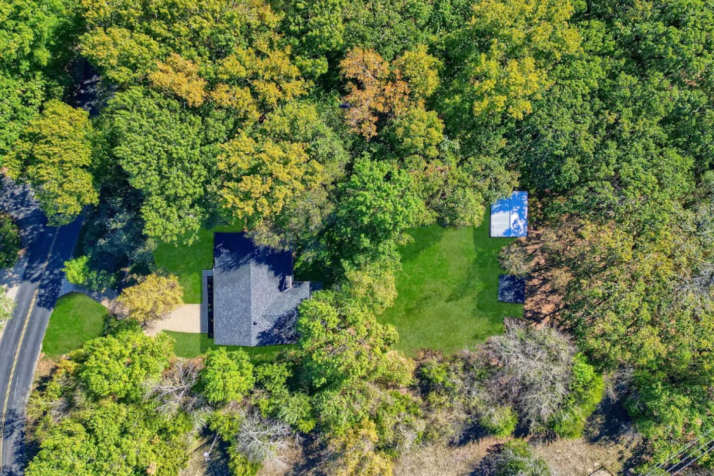 Wide aerial view illustrating the property’s private location near surrounding wooded land.