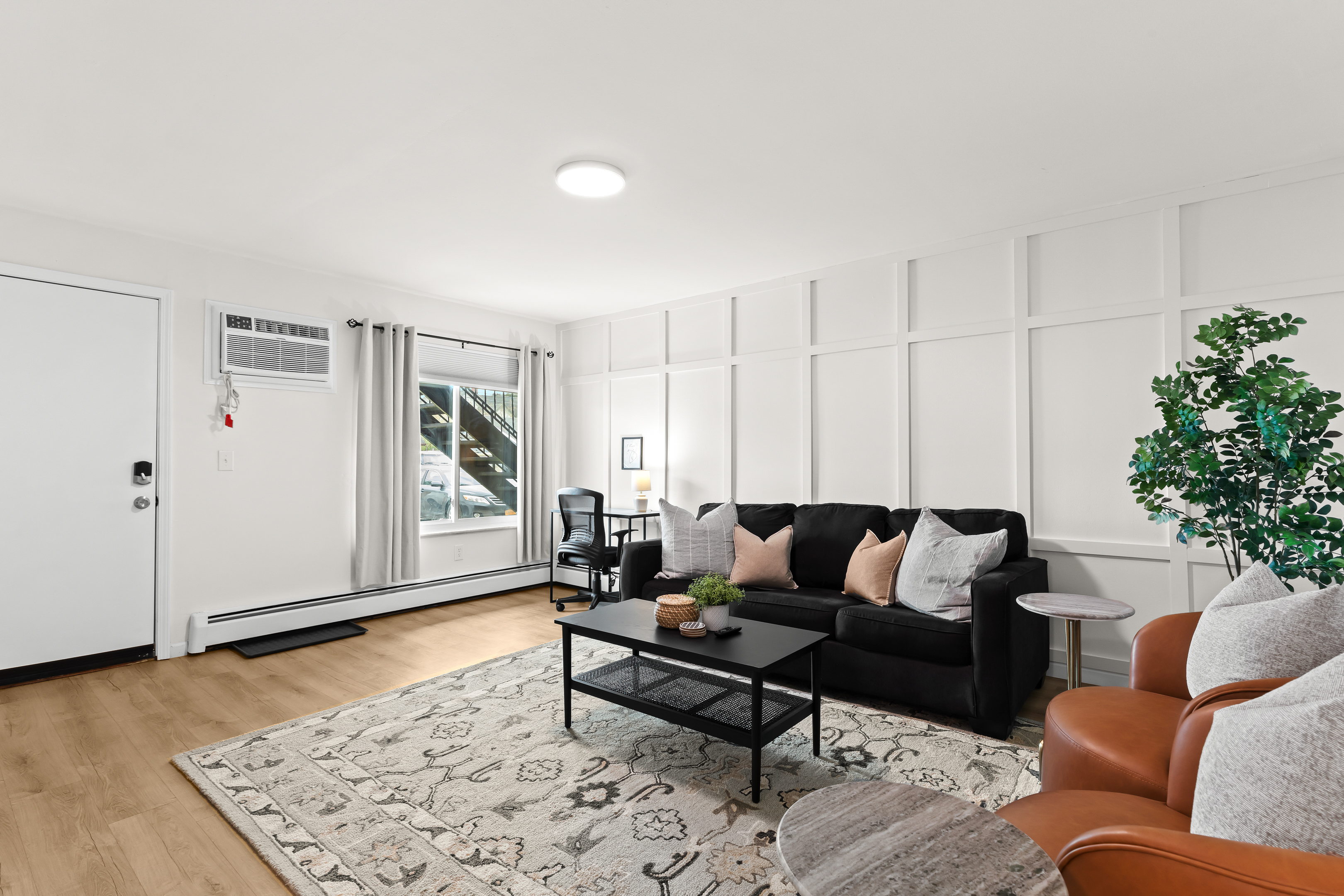 Spacious, stylish living room with cozy seating, chic décor, and a dedicated workspace—perfect for relaxing or working remotely.