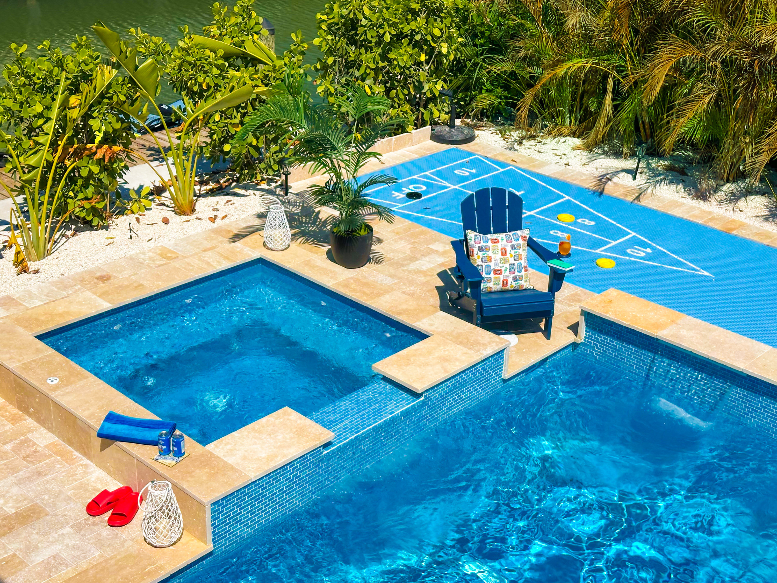 A backyard oasis with a pool and a spa and a shuffleboard court.